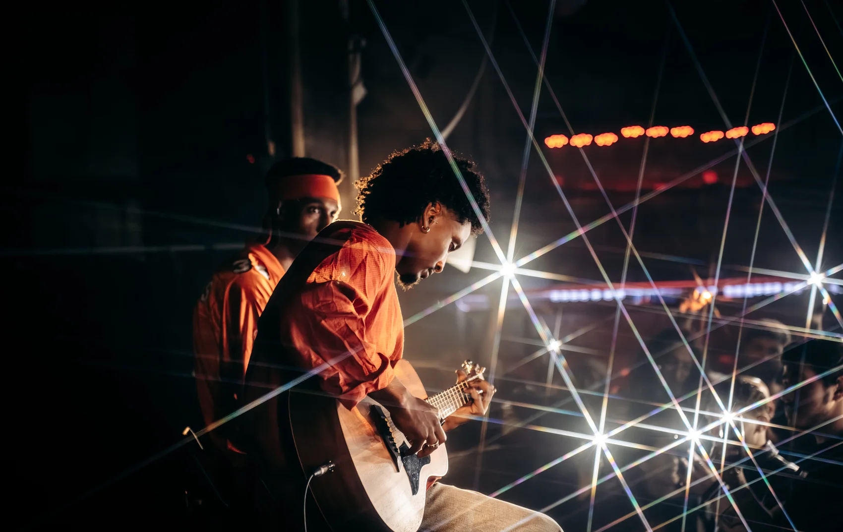 Avraham Lagasa playing guitar amid starburst stage lights
