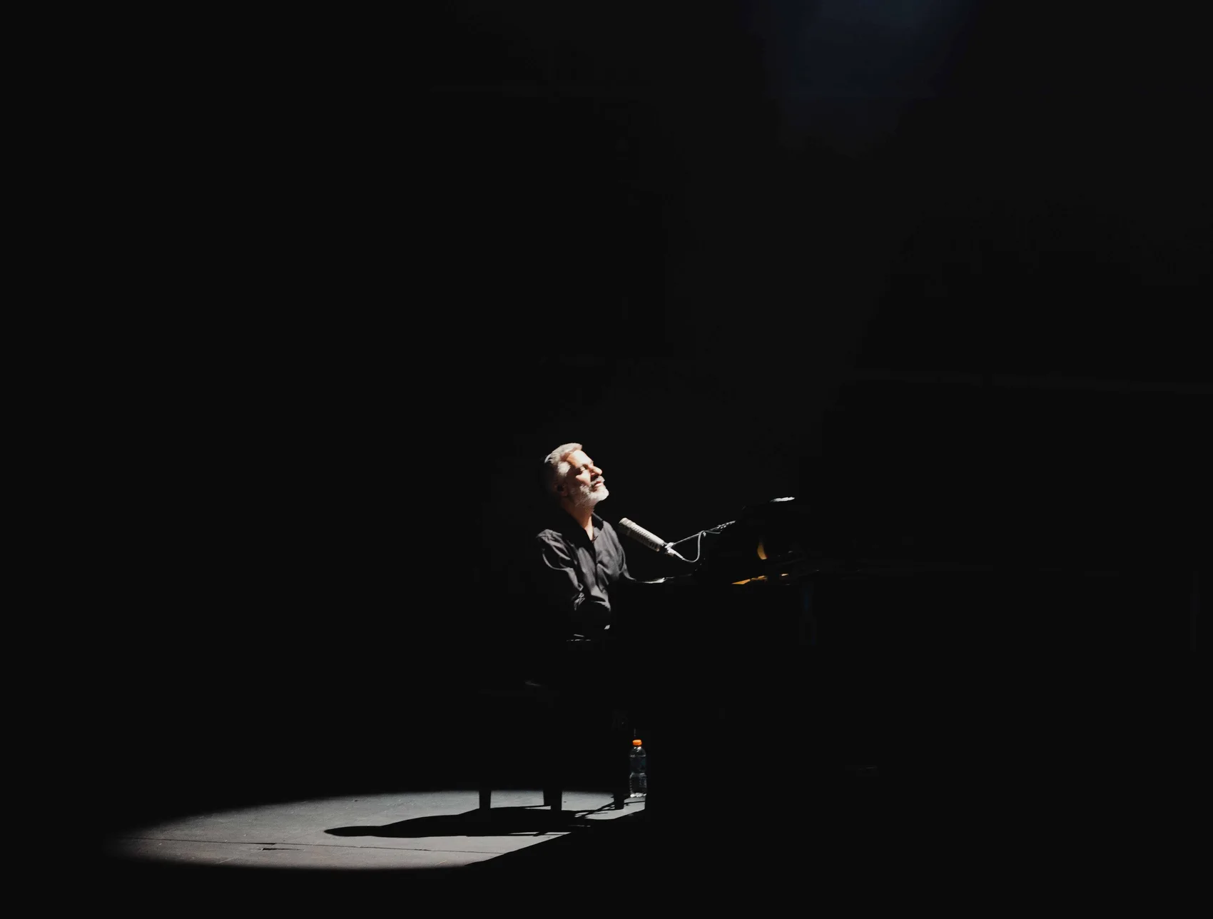 Evyatar Banai alone in a pool of light on a dark stage