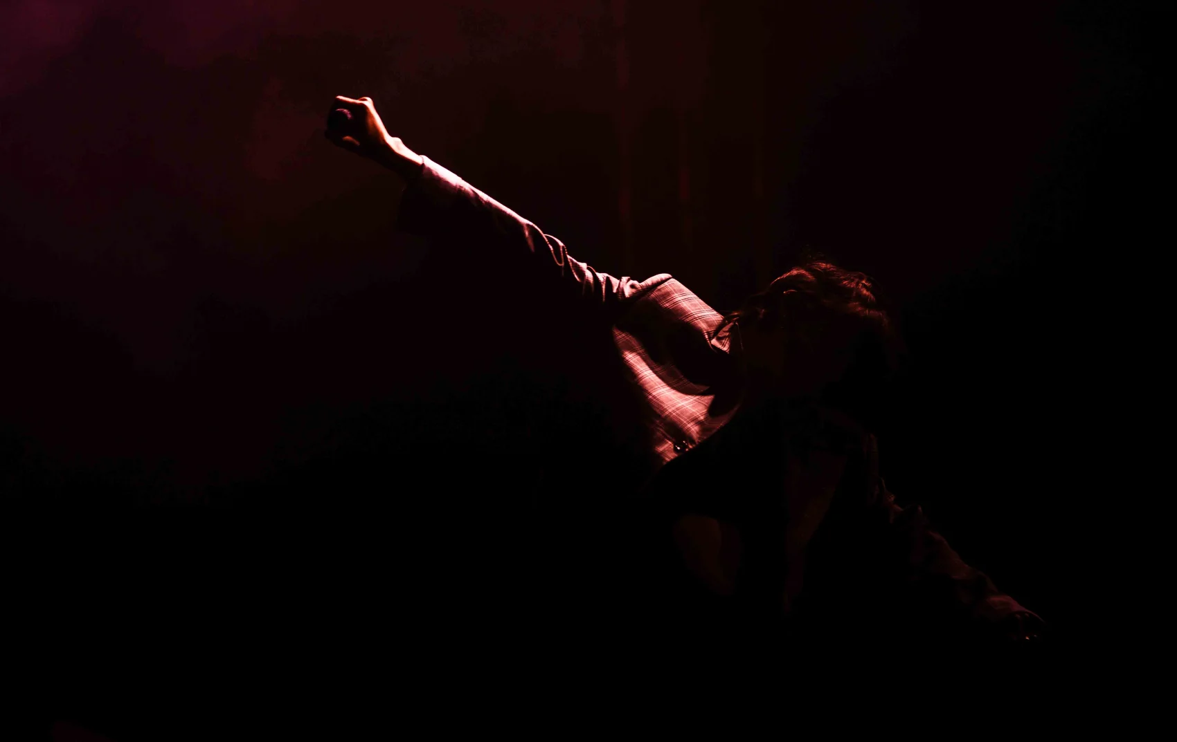 Noga Erez reaching into red stage light